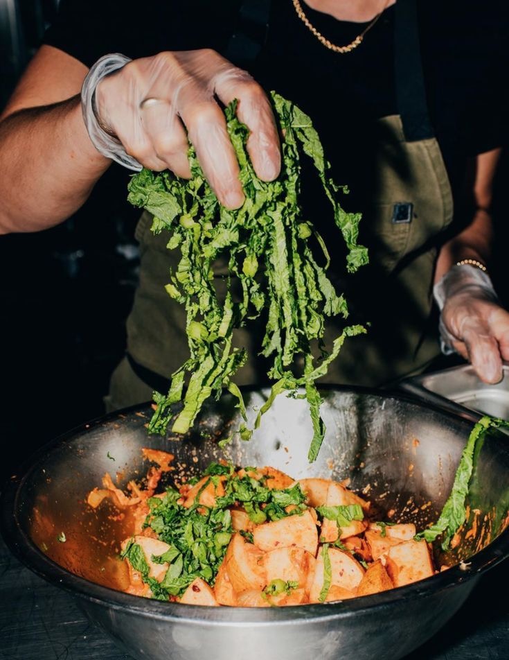 Chef tossing microgreens into a mixing bowl